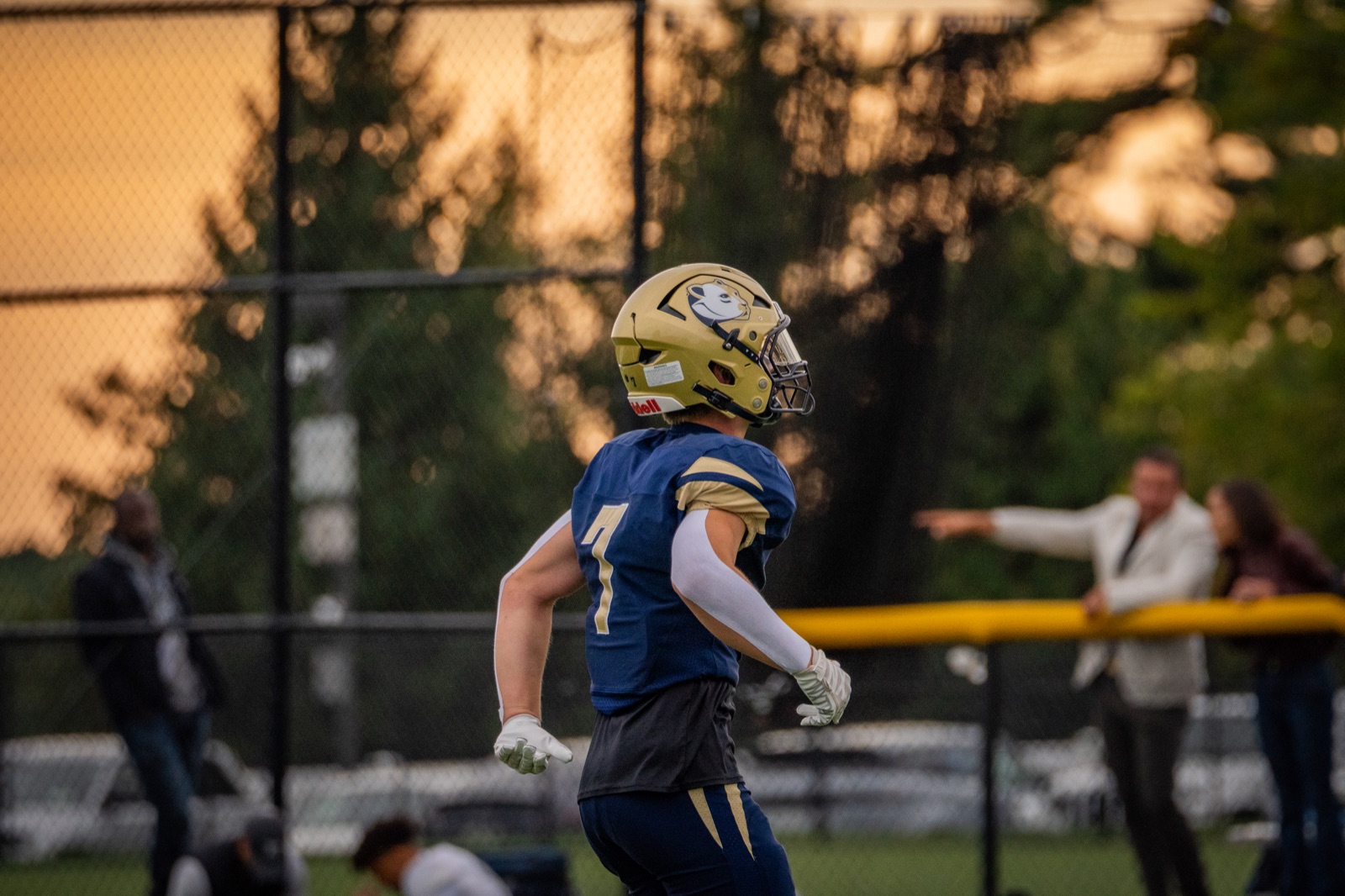 Football player walking across the field at sunset