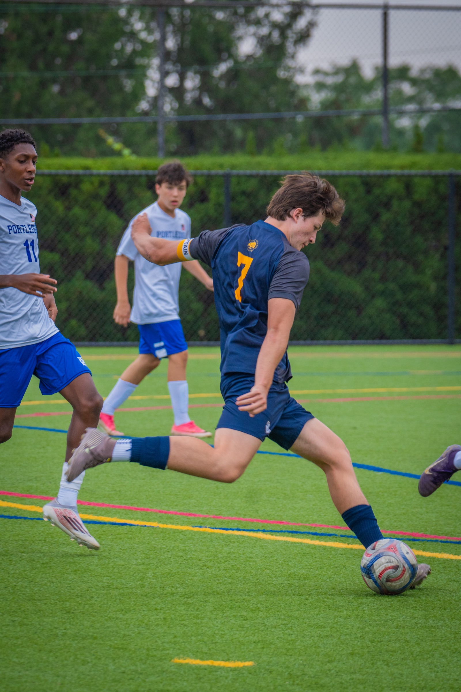 Soccer player striking the ball while defenders close in
